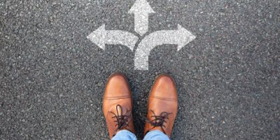 "Close-up of a shoe standing in front of three arrows pointing left, right, and forward, symbolizing career decisions and choosing a path in treasury and financial services."
