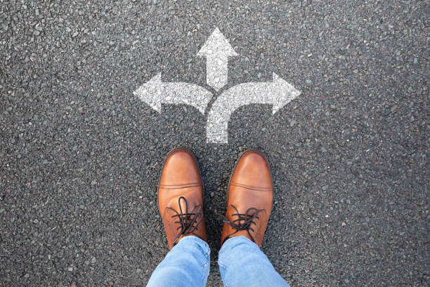 "Close-up of a shoe standing in front of three arrows pointing left, right, and forward, symbolizing career decisions and choosing a path in treasury and financial services."