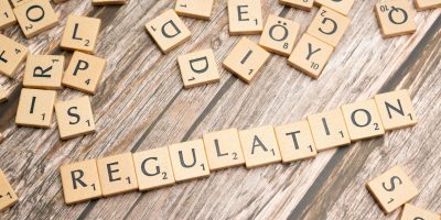 Wooden letter tiles spelling “regulation” on a wooden surface, symbolising Basel 3.1 regulatory change in banking and risk management.